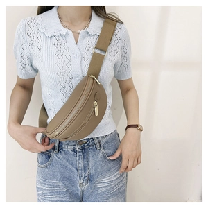Détail du sac banane en cuir grainé beige avec fermeture éclair dorée et sangle toile