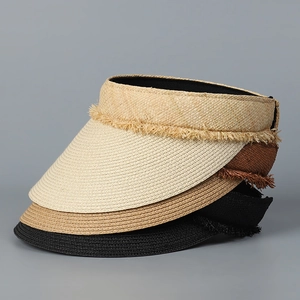 Close-up of three woven straw visors with lace fringe in beige, brown, and black colors