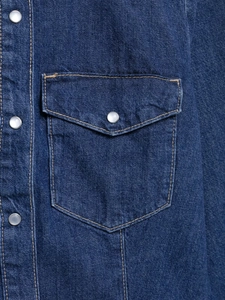 Détail d'une chemise en jean bleu foncé avec surpiqûres et poche à bouton nacré