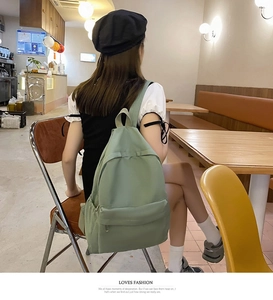 Detailed view of light green casual backpack in a stylish cafe setting with soft lighting