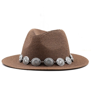 Detail of a brown woven Panama hat with retro silver metal medallion decorative band