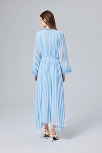 Détail d'une robe plissée bleu clair avec poignets en plumes et broderies de perles fines
