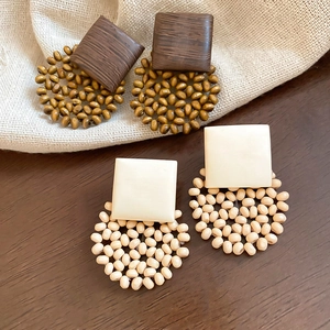 Detailed view of geometric wooden earrings with square plates and beaded circle patterns