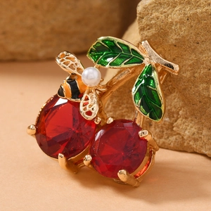 Detailed close-up of cherry brooch with red gemstones, green leaves and a small honey bee