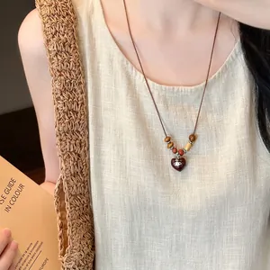 Bohemian coconut wood bead necklace featuring heart pendant with Saturn logo on model