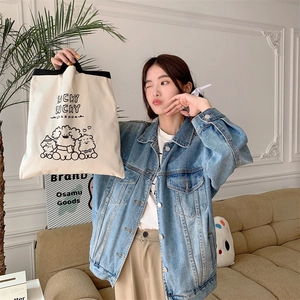 Detail of canvas tote bag with lucky dog print held by model in denim jacket