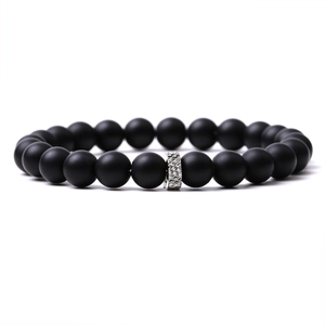Macro shot of matte black stone beads with a textured silver metal cylinder charm