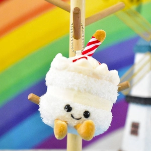 Close-up of cute plush cake pendant with smiley face and striped candle detail
