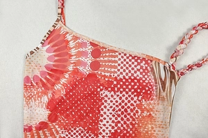 Detailed view of colorful printed dress neck with braided straps and mesh fabric texture