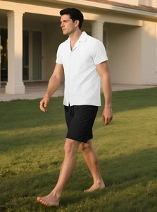 Men's casual white short sleeve shirt and black shorts set walking in a scenic outdoor park