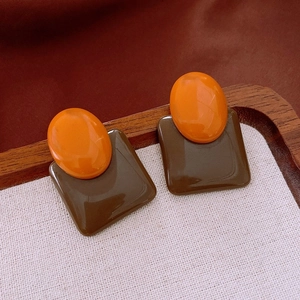 Detailed shot of two-tone resin earrings with orange circles and brown square drops