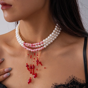 Collier à trois rangs de perles de verre avec pendentif pampille en cristal rouge sur mannequin