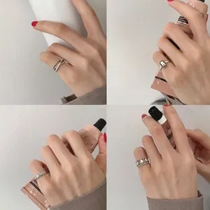 Dettagli di quattro anelli d'argento minimalisti con motivi geometrici e pietra nera
