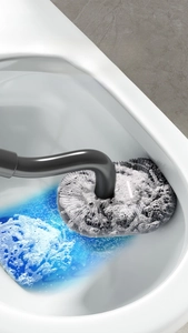 Detail of S-shaped toilet brush with dense grey bristles removing stains with blue liquid