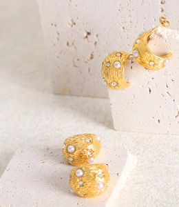 Dettaglio di orecchini e anello vintage dorati con perle e pietre di zircone a stella