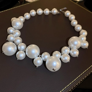 Detail of irregular white pearls on a dark leather surface with a silver metallic clasp