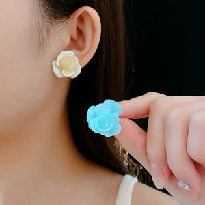 Détail de boucles d'oreilles roses en résine crème et bleue avec tiges en argent