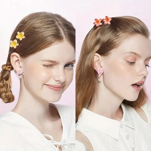 Sweet pink floral earrings and colorful frangipani hair clips on a soft pink background