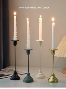 Macro detail of minimalist iron decorative candlesticks in black, gold and cream finishes