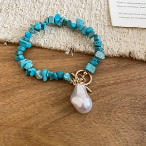 Detailed close-up of bohemian turquoise bead bracelet with baroque pearl and golden toggle clasp
