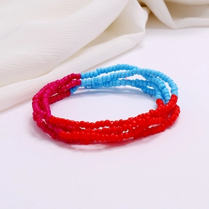 Detail of red and light blue beaded waist chain layers on white fabric texture