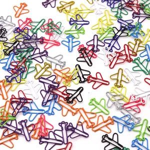 Close-up of colorful airplane shaped paper clips scattered on a clean white background