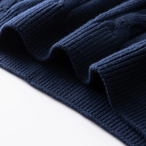 Detailed close-up of navy blue cable knit texture and ribbed hem on cotton sweater