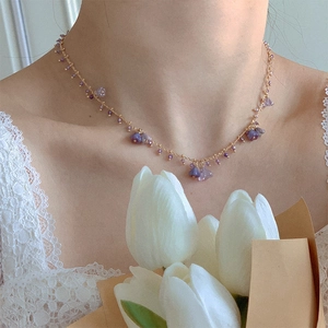 Detail of flower necklace with purple crystals and gold chain on model wearing lace