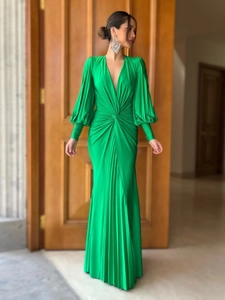 Detail of emerald green pleated dress featuring a deep V-neck and twist waist design