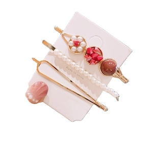 Ensemble de trois barrettes dorées avec coquillage rose et perles sur carte support