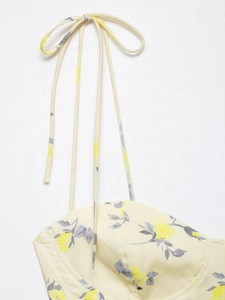 Detailed macro shot of yellow floral poplin top featuring delicate tie-up shoulder straps