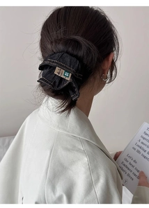 Detail of dark blue denim scrunchie with woven Ace Co. label on a ponytail
