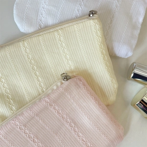 Detailed close-up of quilted fabric texture and metal zipper on pastel cosmetic bags