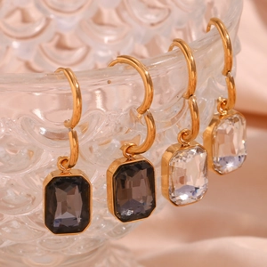 Detailed view of 18K gold earrings with rectangular gray and clear zircon pendants