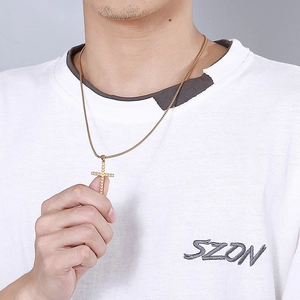 Golden cross pendant necklace with sandblasted finish on a model wearing white shirt