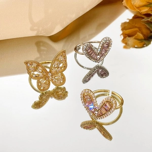 Detailed view of adjustable gold butterfly and heart rings with pink zircon crystals