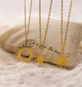 Macro shot of 18K gold plated stainless steel sun and star pendants on soft fabric