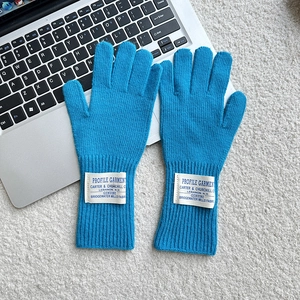 Detail of blue knitted wool gloves with vintage white fabric label on the ribbed cuff