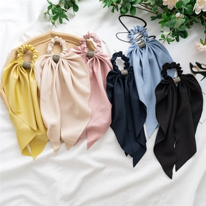 Set of six colorful satin scrunchies with long ribbons and rhinestone accents on white fabric