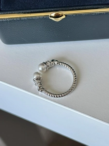 Macro shot of silver twisted cable ring with twin pearls and diamond accents on white