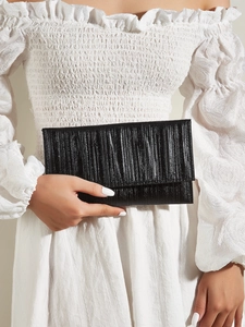 Detail of elegant black pleated clutch bag featuring vertical textures and metallic finish