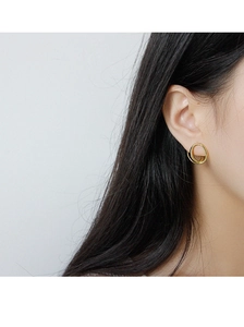 Close-up of a model wearing minimalist golden geometric circular sterling silver earrings