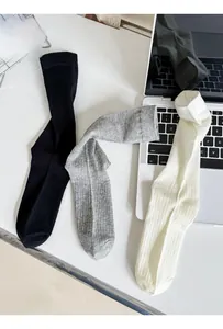 Detailed knit texture of combed cotton crew socks in black, grey, and off-white colors
