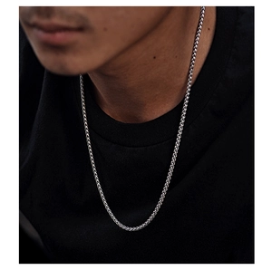 Detail view of a silver titanium steel woven cuban link necklace worn on model neck