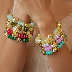Macro detail of layered colorful acrylic beaded bracelets with gold irregular metal charms