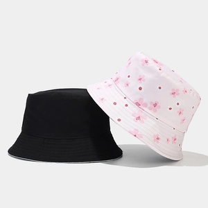Detail showing two reversible sun hats in solid black and pink floral cherry blossom pattern