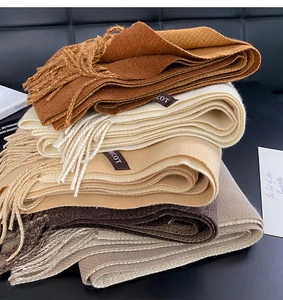 Close-up of stacked winter scarves in brown and beige tones with soft tassel details