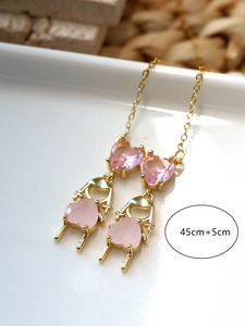 Collier double rang doré avec pierres en cœur rose et pendentifs fille sur un plateau