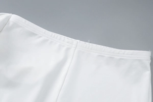 Detailed close-up of double-needle stitching on the waist of a white sleeveless summer suit