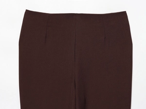 Detail view of deep brown trousers waist showing fine twill fabric texture on white background